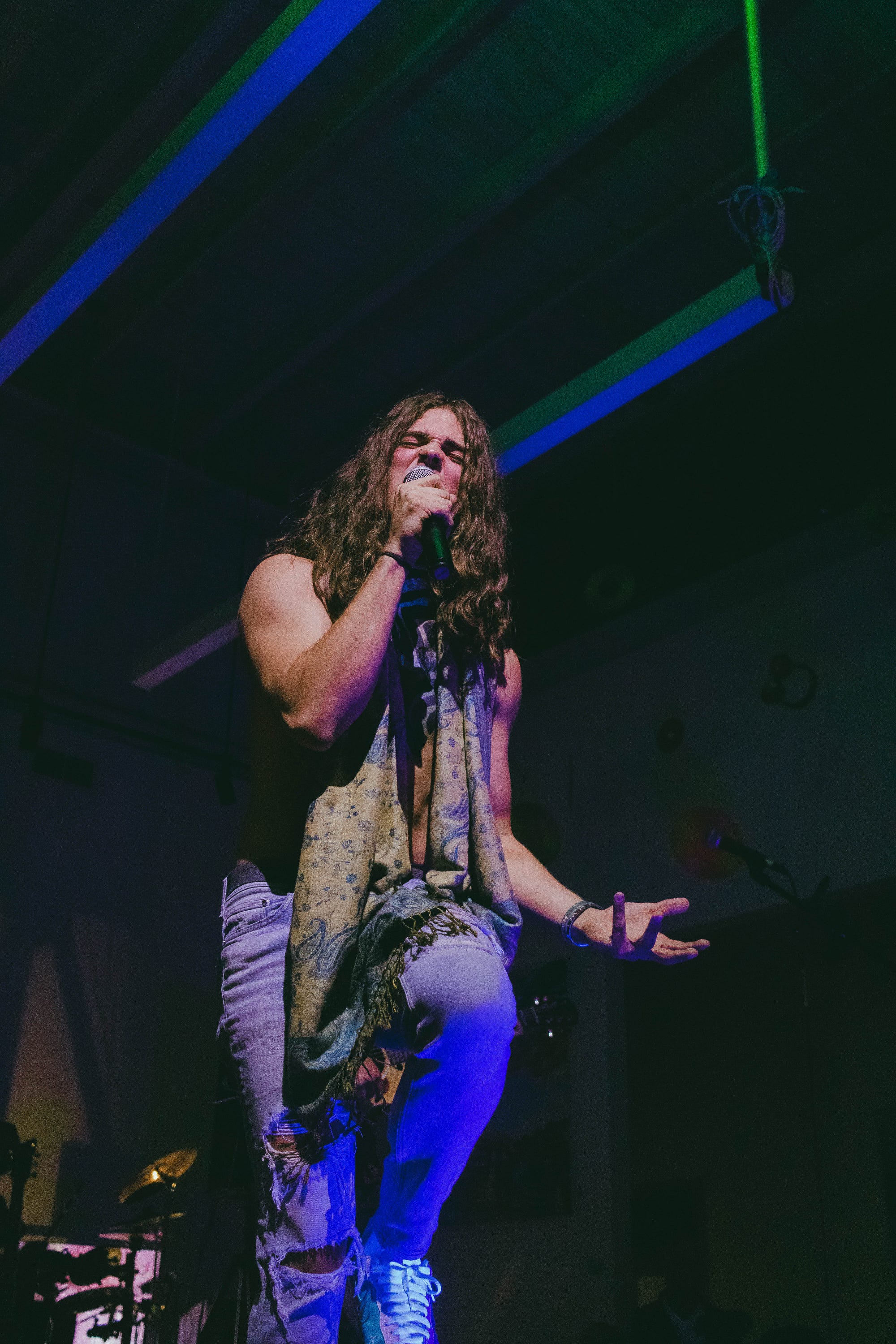 Jourdan Blue performing live with a paisley scarf, belting into the microphone