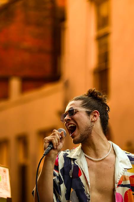 Jourdan Blue belting outdoors against a sunlit building in the Chasin' music video