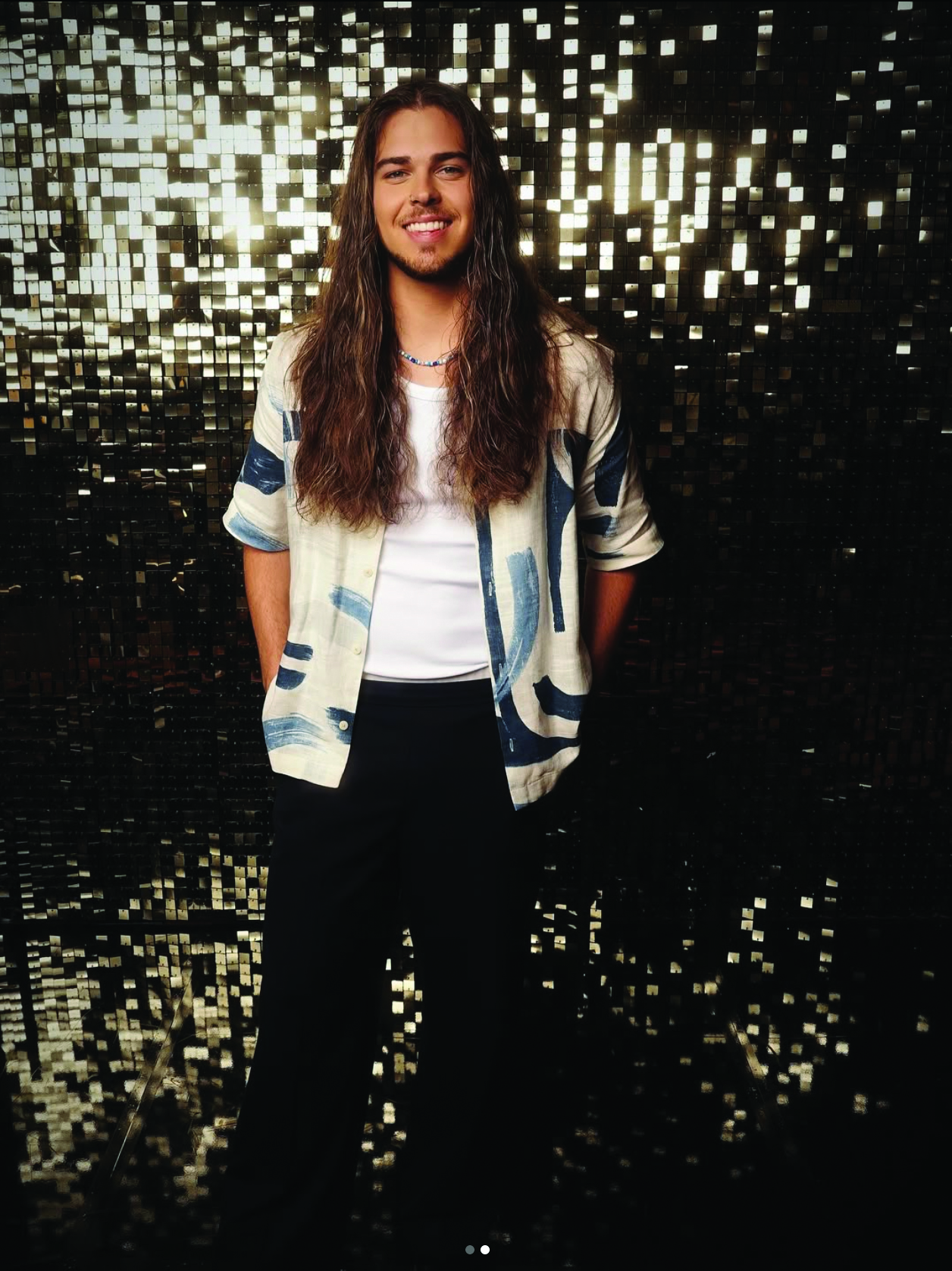 Jourdan Blue smiling against a gold sequin backdrop