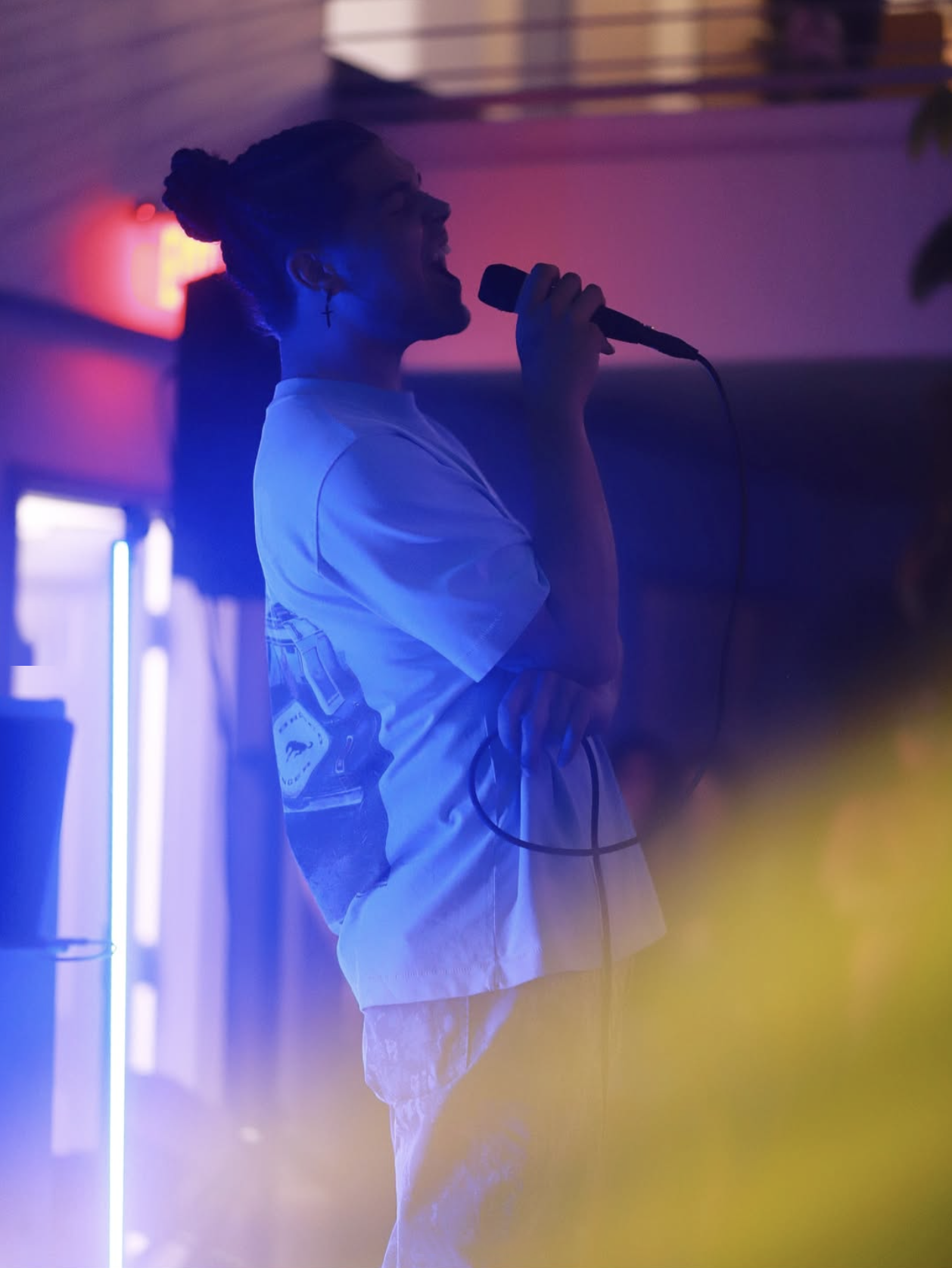 Jourdan Blue singing in profile under blue and red club light