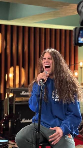 Jourdan Blue singing during a studio session in a blue hoodie